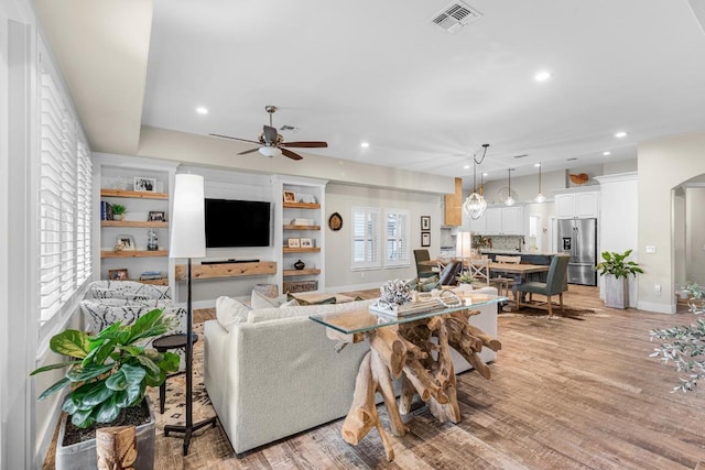 living area with light wood-type flooring, visible vents, arched walkways, and recessed lighting