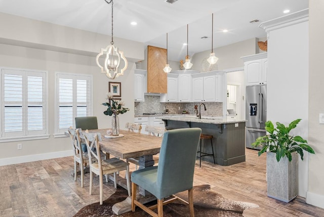 dining area featuring baseboards, an inviting chandelier, visible vents, and light wood-style floors