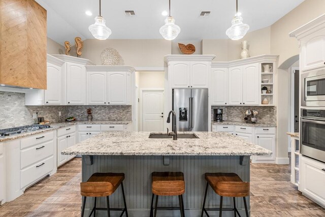 13525 Queen Johanna Ct, Corpus Christi, TX 78418 - kitchen featuring appliances with stainless steel finishes, tasteful backsplash, white cabinets, a breakfast bar area, and vaulted ceiling