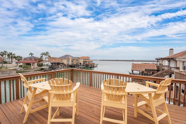 wooden deck featuring a residential view, outdoor dining area, and a water view