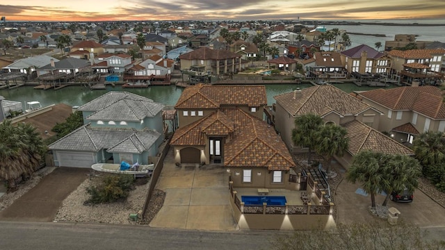 aerial view at dusk with a water view and a residential view