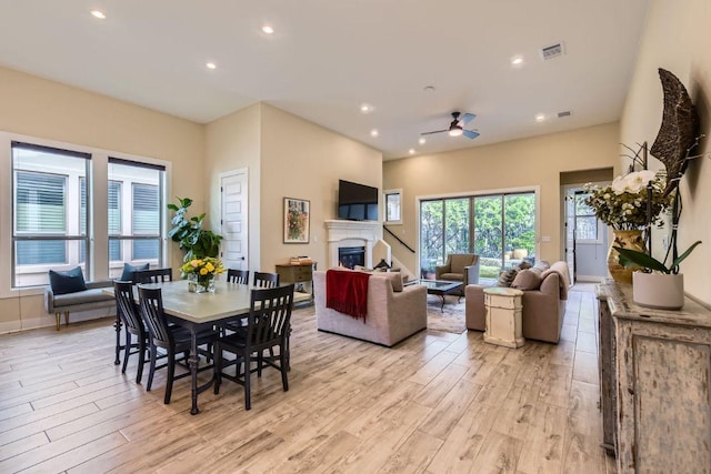 dining room featuring light wood finished floors, recessed lighting, visible vents, and a glass covered fireplace