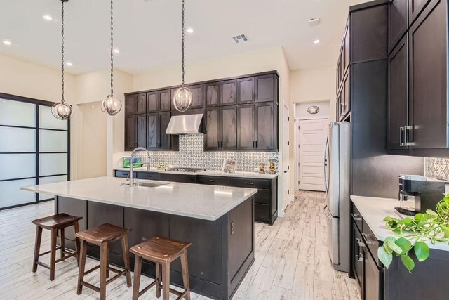 kitchen featuring visible vents, appliances with stainless steel finishes, a kitchen breakfast bar, under cabinet range hood, and a sink