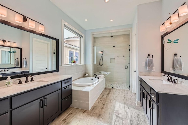 full bath with wood finished floors, a stall shower, a sink, and a bath