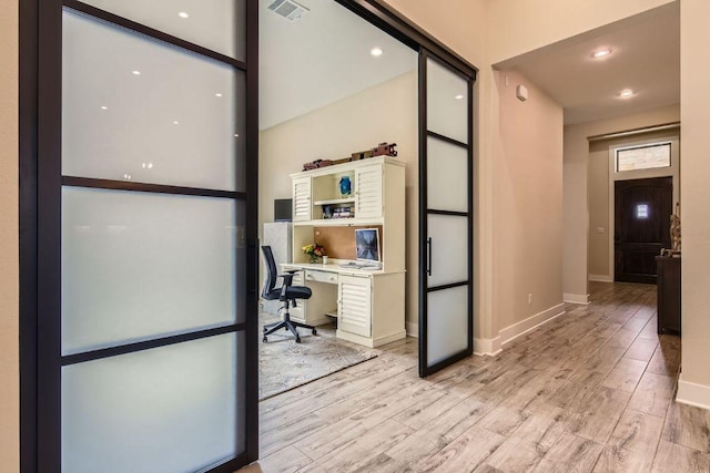 unfurnished office with light wood-style flooring, visible vents, and baseboards