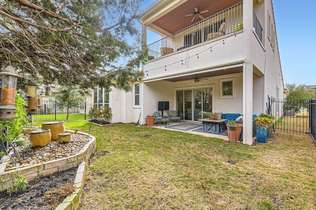 rear view of property featuring a lawn, a fenced backyard, a balcony, and a ceiling fan