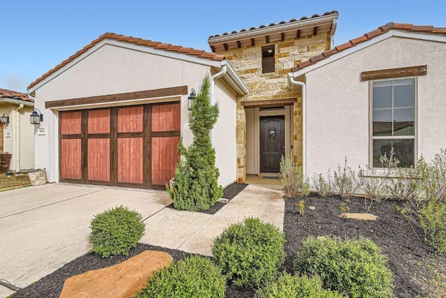 mediterranean / spanish house featuring a garage, stone siding, concrete driveway, a tiled roof, and stucco siding