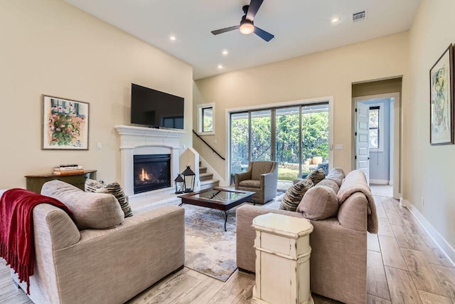 living room with ceiling fan, recessed lighting, baseboards, light wood-type flooring, and a glass covered fireplace