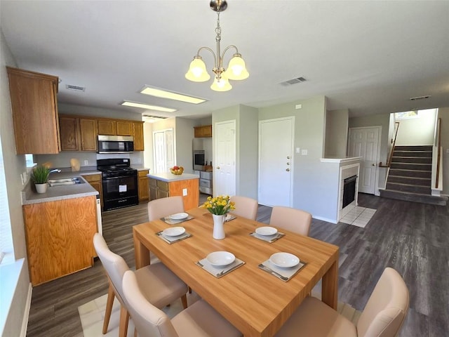 4533 Corran Ferry Loop, Austin, TX 78749 - dining room with dark wood finished floors, a fireplace with flush hearth, a chandelier, and stairs