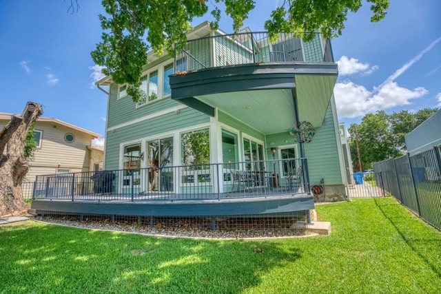 back of property featuring a lawn, a wooden deck, and fence