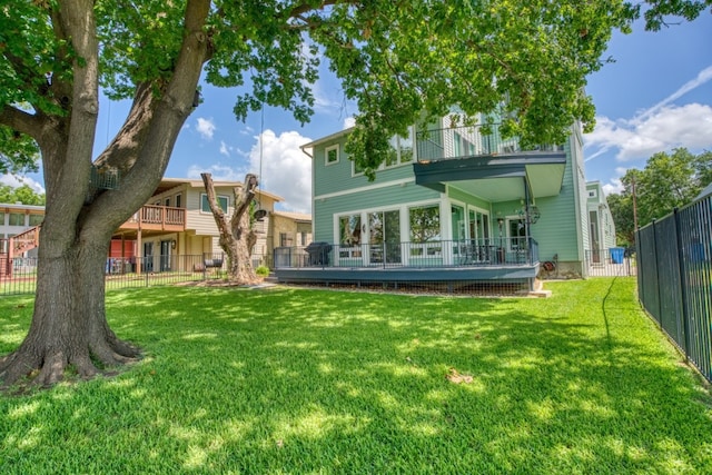 back of property featuring a balcony, fence, a deck, and a yard