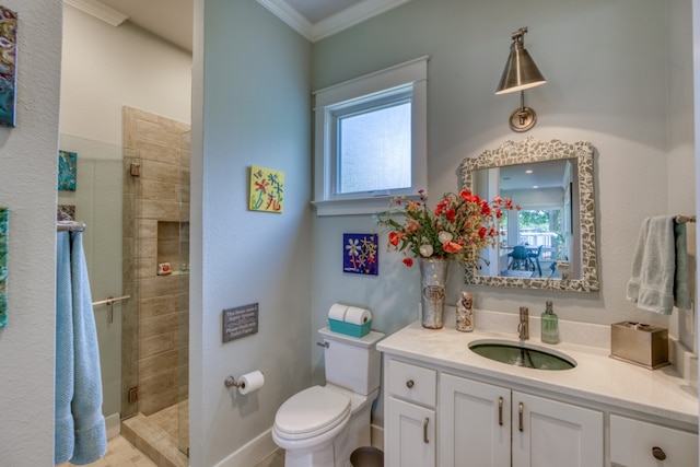 bathroom with a stall shower, baseboards, toilet, ornamental molding, and vanity