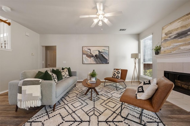 living area featuring baseboards, visible vents, wood finished floors, and a tile fireplace