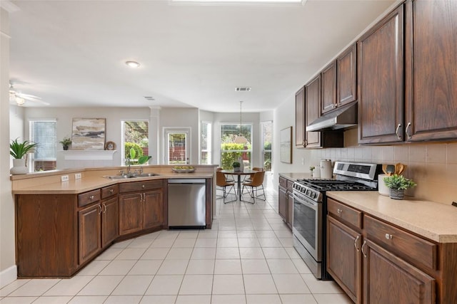 kitchen with light tile patterned floors, stainless steel appliances, tasteful backsplash, a sink, and under cabinet range hood