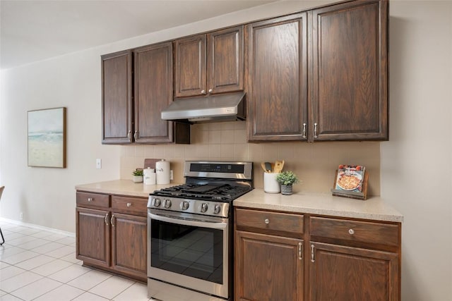 kitchen with stainless steel gas stove, light countertops, tasteful backsplash, and under cabinet range hood