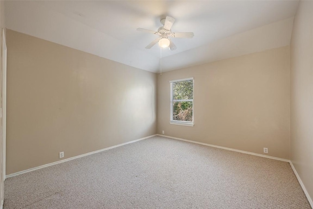 carpeted empty room featuring lofted ceiling, a ceiling fan, and baseboards