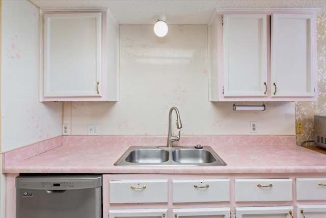 kitchen featuring light countertops, stainless steel dishwasher, a sink, and white cabinets