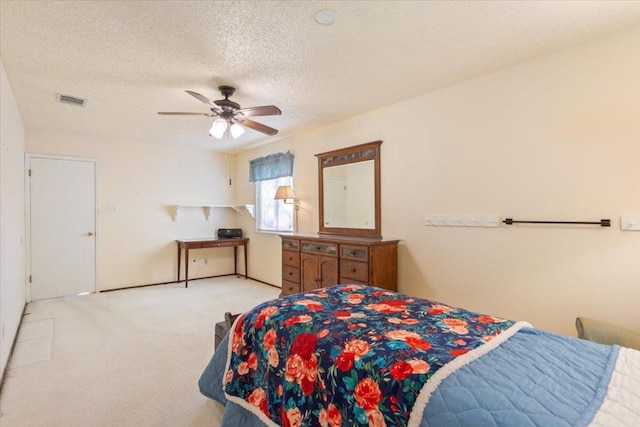 carpeted bedroom featuring a textured ceiling, visible vents, and a ceiling fan