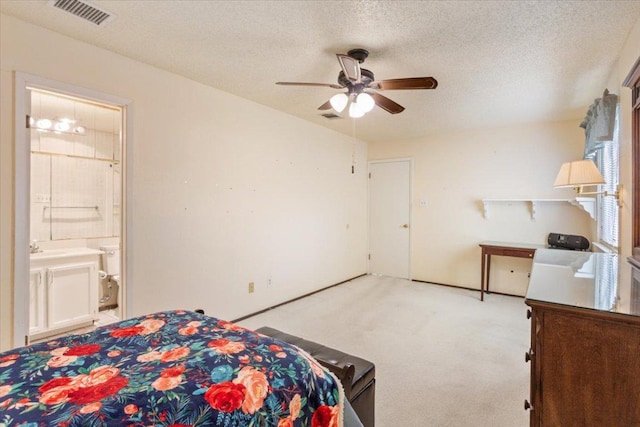 bedroom with connected bathroom, visible vents, a textured ceiling, and light colored carpet