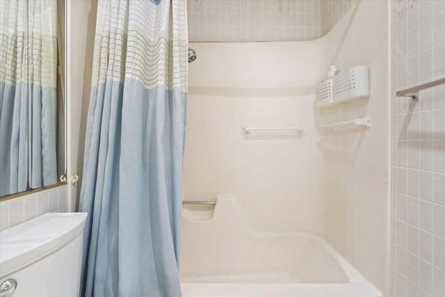 bathroom featuring toilet, a shower with shower curtain, and tile walls