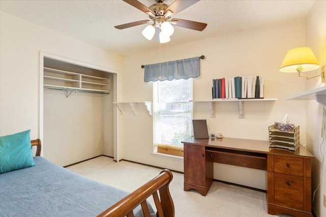 bedroom featuring a closet, light colored carpet, ceiling fan, and a textured ceiling