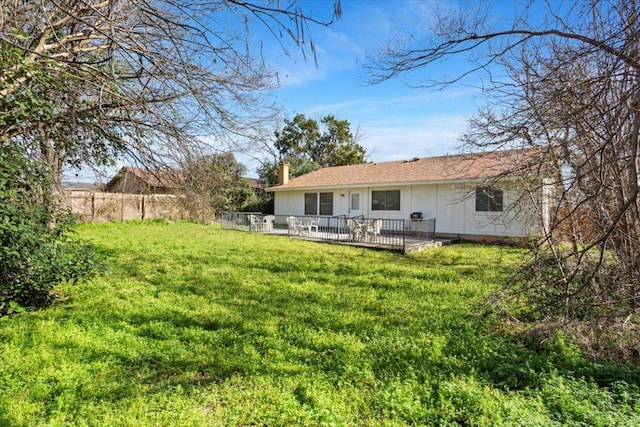 back of house featuring a chimney, fence, and a lawn