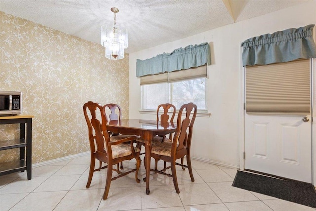 dining area featuring wallpapered walls, baseboards, an inviting chandelier, tile patterned flooring, and a textured ceiling