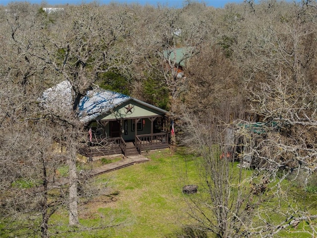 view of yard featuring covered porch and a view of trees