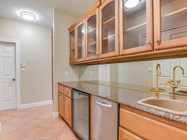 kitchen with light tile patterned floors, beverage cooler, stone counters, a sink, and glass insert cabinets