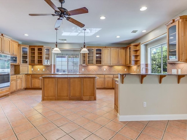 kitchen featuring light tile patterned floors, visible vents, appliances with stainless steel finishes, and a kitchen breakfast bar