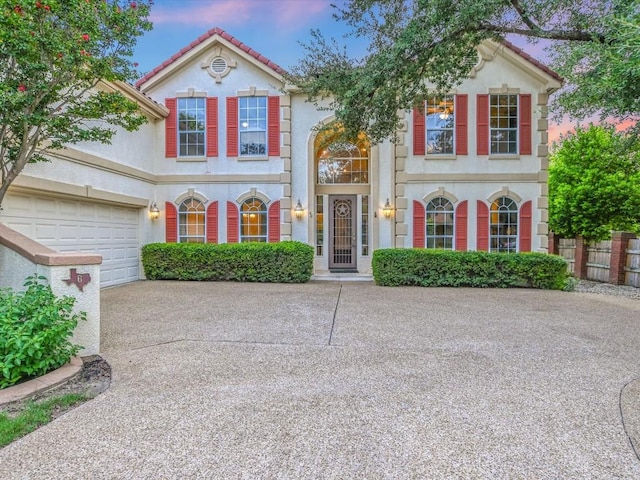 view of front of house featuring a tile roof, fence, driveway, and stucco siding