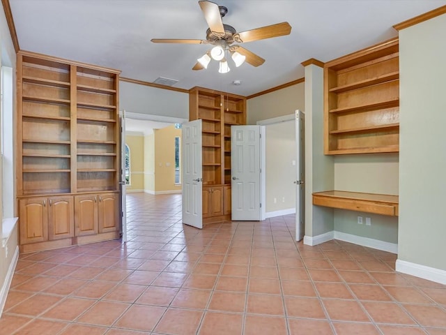 interior space with visible vents, built in desk, crown molding, light tile patterned floors, and baseboards