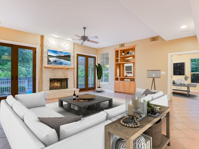 living room with a stone fireplace, tile patterned floors, french doors, and visible vents