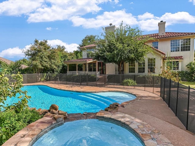 view of swimming pool with a patio, fence, and a pool with connected hot tub