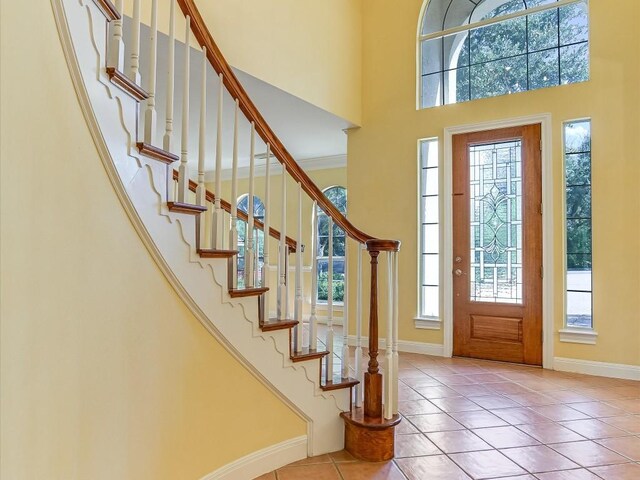 entryway with tile patterned flooring, a high ceiling, and baseboards