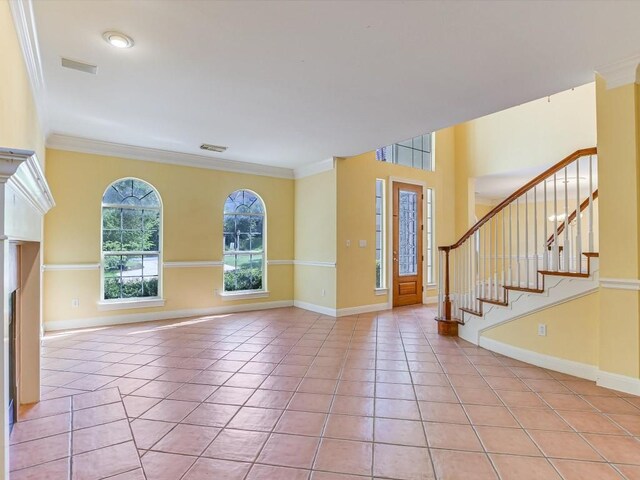 foyer with light tile patterned floors, baseboards, visible vents, ornamental molding, and stairs