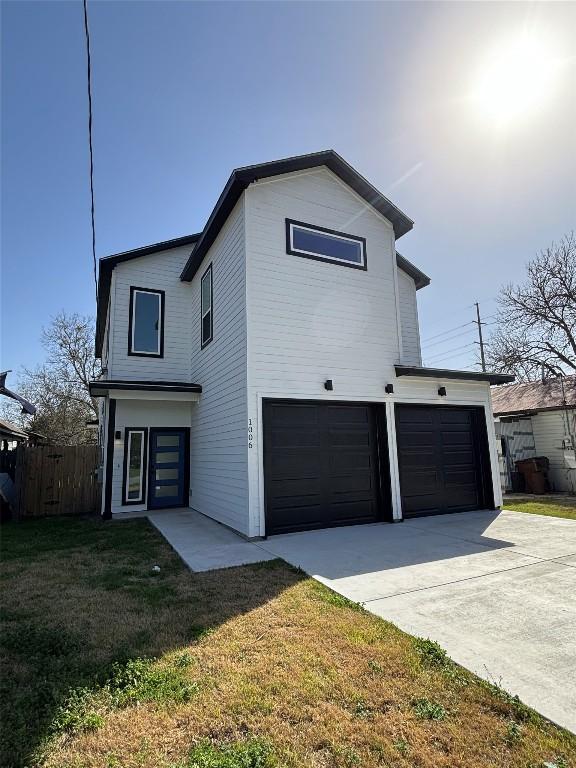 view of front of home featuring a garage, a front yard, concrete driveway, and fence