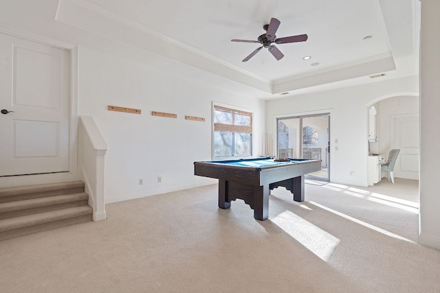 game room featuring arched walkways, light carpet, visible vents, ornamental molding, and a raised ceiling