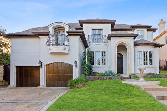 view of front of house with aphalt driveway, an attached garage, a balcony, stucco siding, and a front lawn