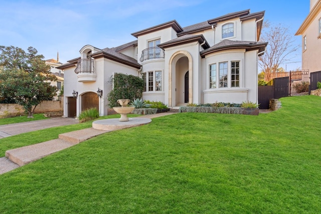 mediterranean / spanish-style home featuring a balcony, stucco siding, fence, and a front yard