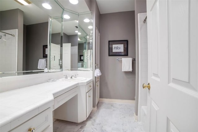 bathroom with baseboards, walk in shower, and vanity