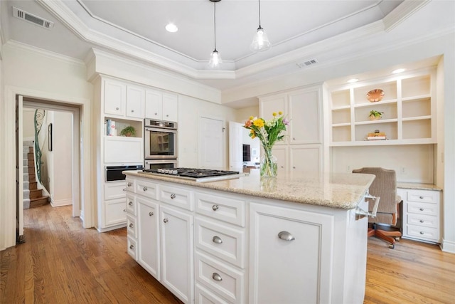 kitchen with visible vents, a kitchen island, white cabinetry, open shelves, and built in desk