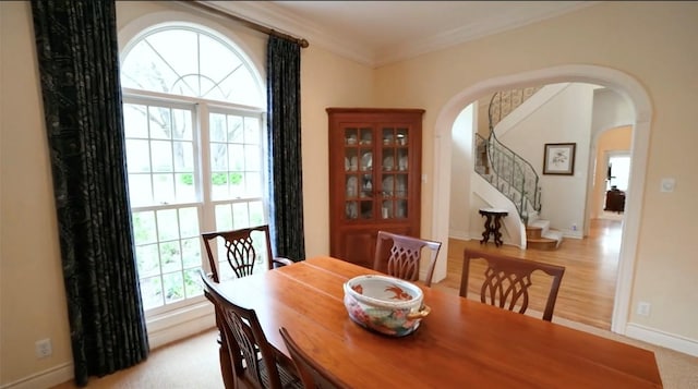 dining area with baseboards, stairs, arched walkways, and ornamental molding