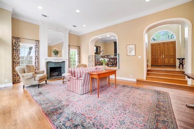 living room with baseboards, visible vents, a premium fireplace, ornamental molding, and wood finished floors