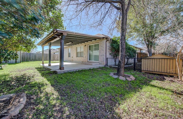 exterior space with a patio, a fenced backyard, a yard, an outdoor structure, and brick siding