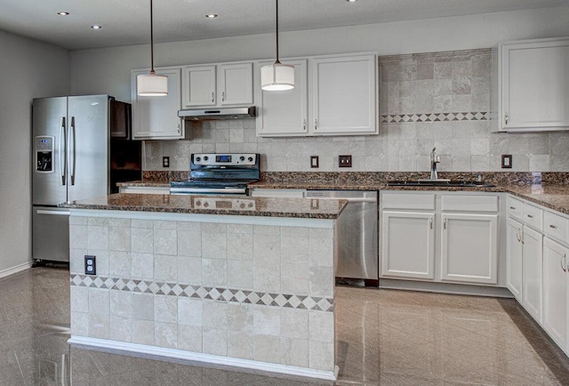 kitchen featuring appliances with stainless steel finishes, a sink, under cabinet range hood, and granite finish floor