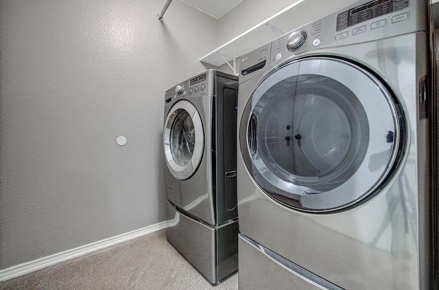 laundry room with laundry area, baseboards, washer and clothes dryer, and a textured wall