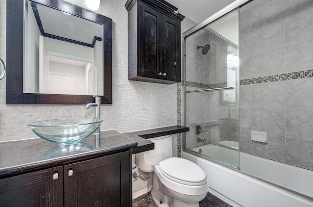 full bath featuring tasteful backsplash, vanity, toilet, and bath / shower combo with glass door