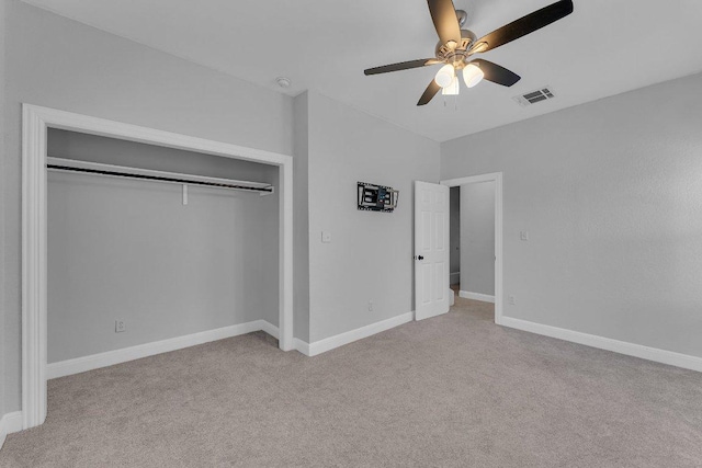 unfurnished bedroom featuring baseboards, visible vents, light colored carpet, ceiling fan, and a closet