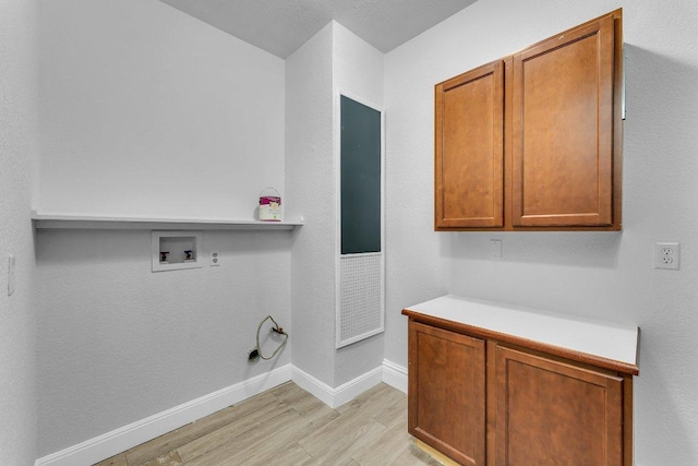 laundry area featuring light wood-style floors, hookup for a washing machine, cabinet space, and baseboards